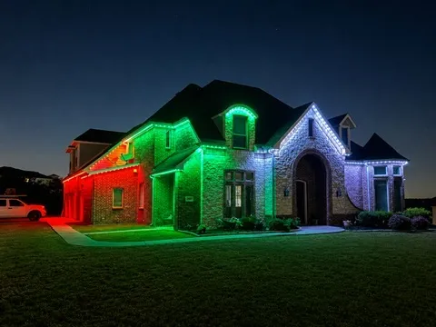 The same home at Christmas, rooflines running alternating red, green, and white