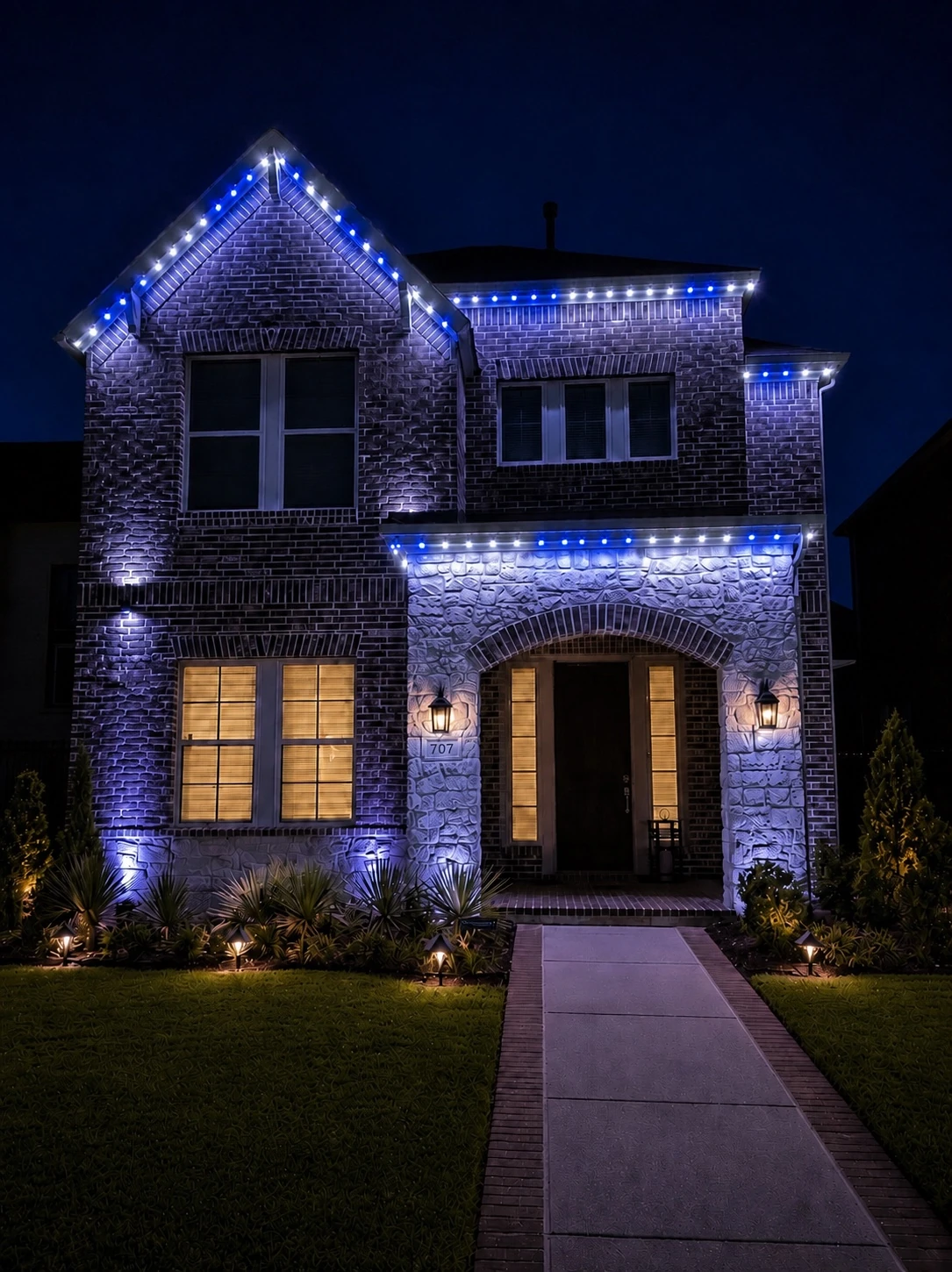 An Iron Acre installation on game night: a brick and stone home lit in alternating blue and white